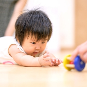 おもちゃに手を伸ばす赤ちゃん